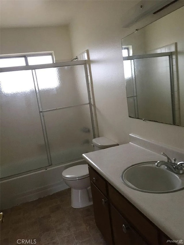 full bath featuring toilet, vanity, and shower / bath combination with glass door