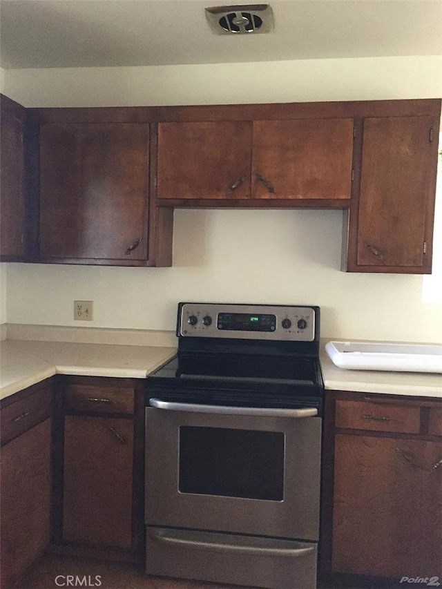 kitchen featuring electric stove, light countertops, and dark brown cabinetry