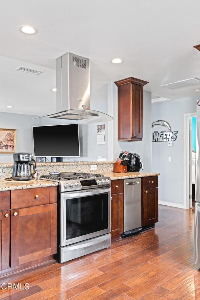 1257 S G St, Oxnard, CA 93033 - kitchen with wood finished floors, stainless steel gas stove, island range hood, and light stone countertops