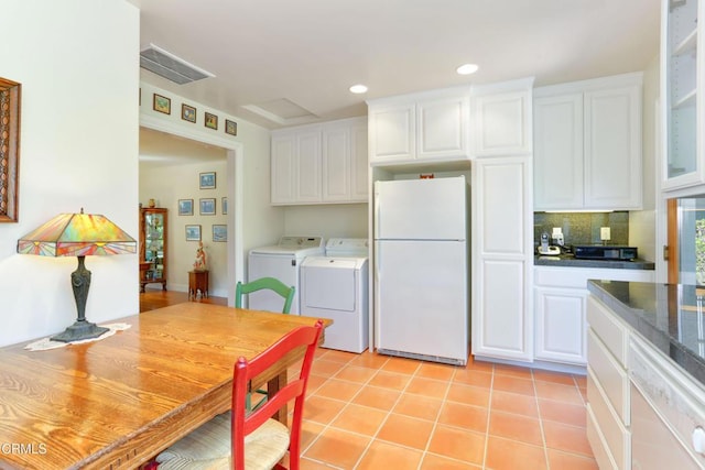 kitchen with visible vents, white cabinets, freestanding refrigerator, washer and clothes dryer, and light tile patterned flooring