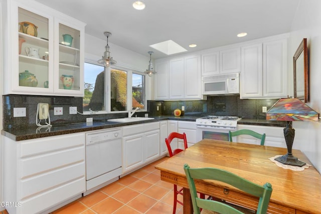 kitchen with white cabinets, white appliances, a sink, and a skylight