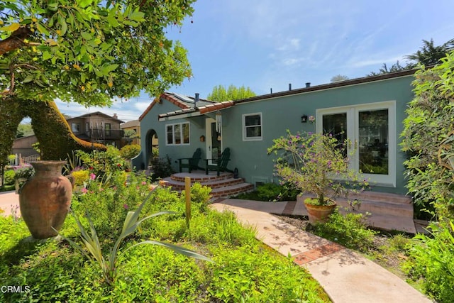 view of front of home with a tile roof, solar panels, and stucco siding