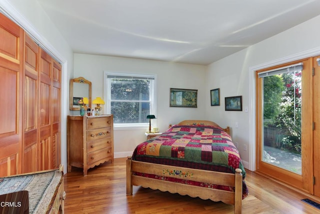bedroom with access to outside, light wood-style floors, multiple windows, and visible vents