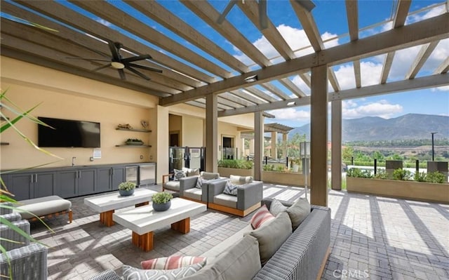 view of patio with area for grilling, outdoor lounge area, a mountain view, a ceiling fan, and a pergola