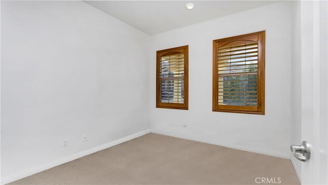 spare room featuring baseboards and light colored carpet