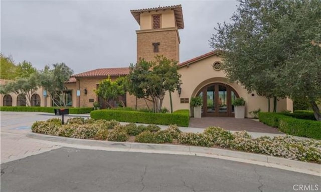 exterior space with stucco siding, a tiled roof, and french doors