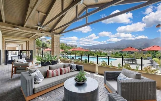 view of patio / terrace featuring a mountain view, ceiling fan, an outdoor hangout area, and an outdoor pool