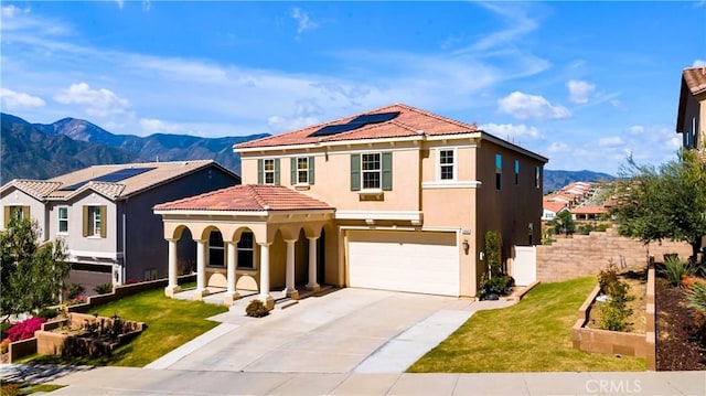 mediterranean / spanish home with driveway, a mountain view, an attached garage, solar panels, and stucco siding