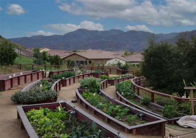 surrounding community featuring a mountain view, a vegetable garden, and fence