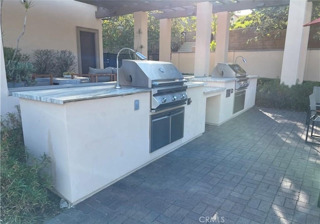 view of patio with exterior kitchen, area for grilling, and a pergola
