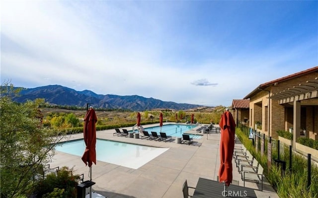 community pool with a patio, a mountain view, and fence