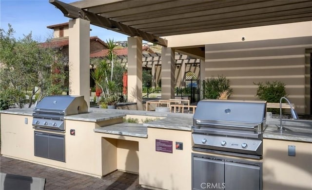 view of patio featuring exterior kitchen, a sink, and a grill