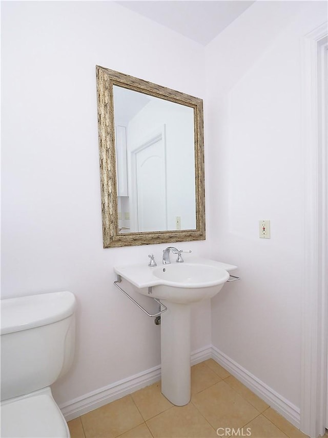 bathroom with tile patterned flooring, baseboards, and toilet