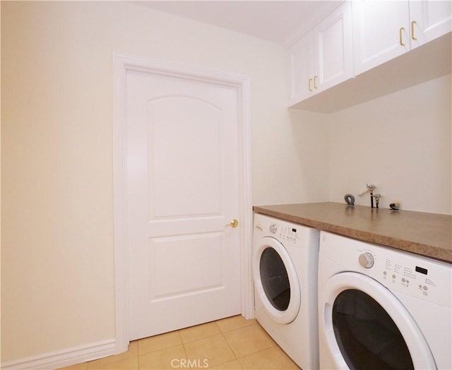 washroom with light tile patterned floors, washing machine and dryer, and cabinet space