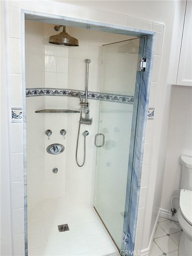 bathroom featuring toilet, a shower stall, and tile patterned flooring