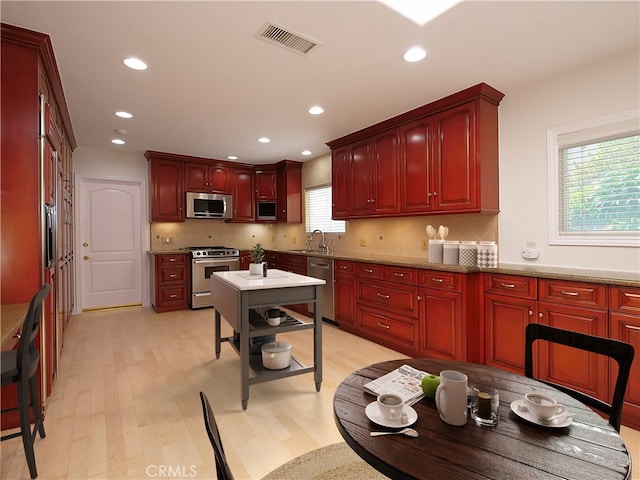 kitchen with light wood-type flooring, recessed lighting, dark brown cabinets, visible vents, and stainless steel appliances