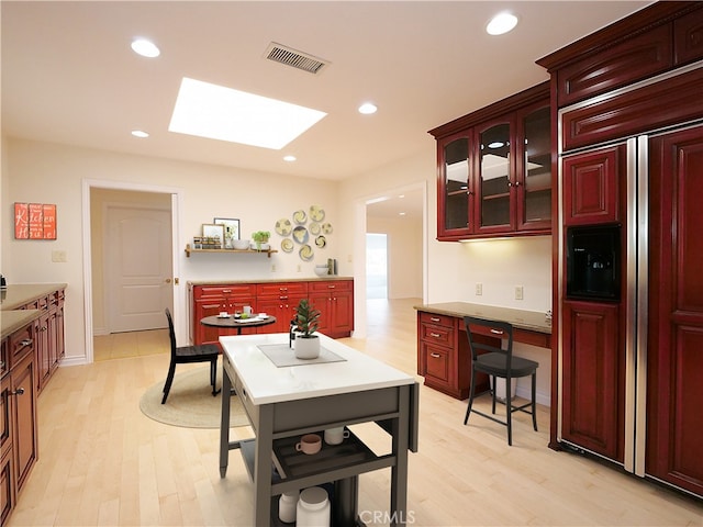 kitchen with light wood-style flooring, visible vents, reddish brown cabinets, and a skylight