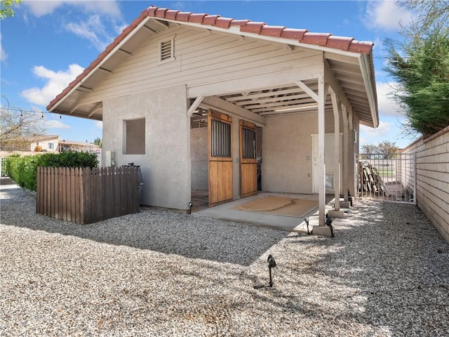 rear view of property featuring a tile roof and stucco siding