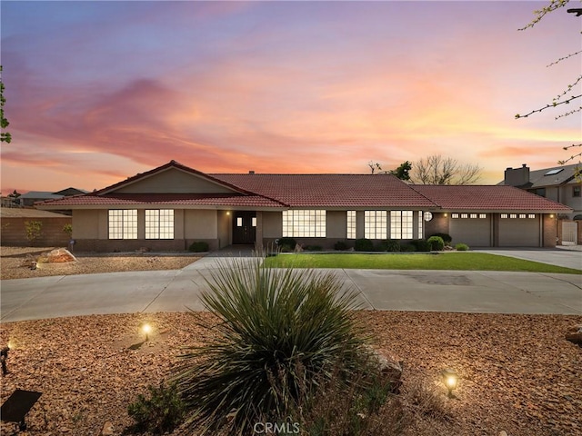 view of front of house featuring a tile roof, an attached garage, driveway, and stucco siding