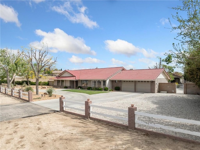 view of front of home featuring driveway, an attached garage, a fenced front yard, a tile roof, and a gate
