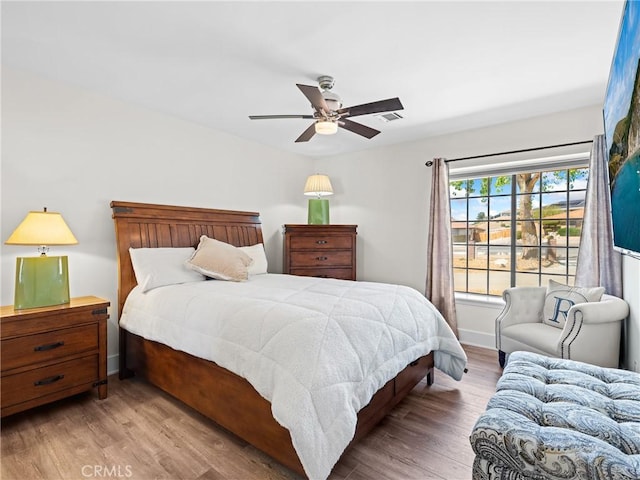 bedroom featuring visible vents, baseboards, a ceiling fan, and wood finished floors