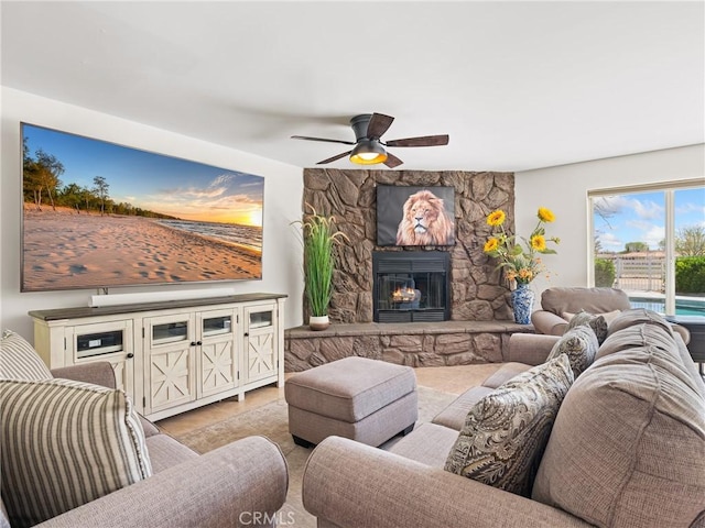 living area featuring a stone fireplace and a ceiling fan