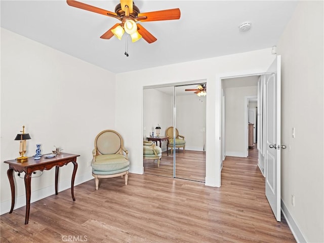 sitting room featuring light wood-style flooring, ceiling fan, and baseboards