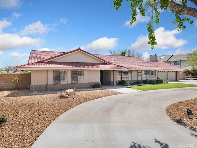 single story home with stucco siding, a tiled roof, an attached garage, and curved driveway
