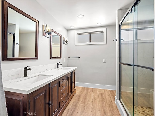 full bathroom featuring a shower stall, wood finished floors, double vanity, and a sink