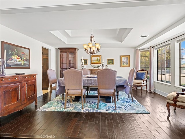 dining room featuring a tray ceiling, an inviting chandelier, dark wood-style floors, and visible vents