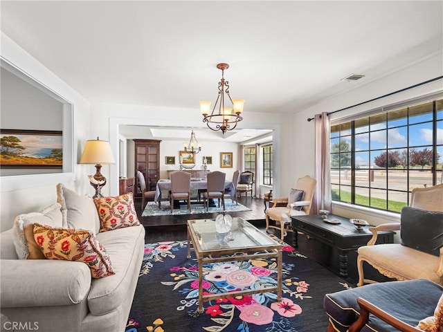 living area featuring wood finished floors, a notable chandelier, and visible vents