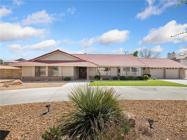 ranch-style house with a tiled roof, driveway, a garage, and stucco siding