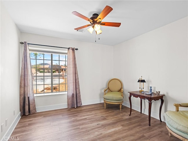 sitting room with wood finished floors, baseboards, a ceiling fan, and visible vents