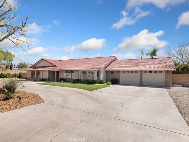 ranch-style home with stucco siding, driveway, an attached garage, a front yard, and a tiled roof