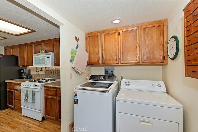 washroom with washer and dryer, light wood-style floors, a textured ceiling, and laundry area