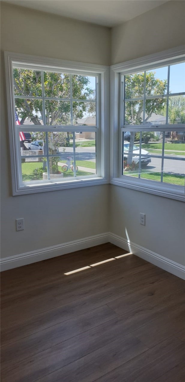 spare room with dark wood finished floors and baseboards