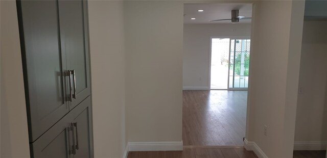 corridor featuring baseboards, recessed lighting, and wood finished floors