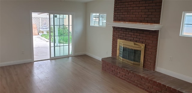 unfurnished living room featuring baseboards, wood finished floors, and a fireplace