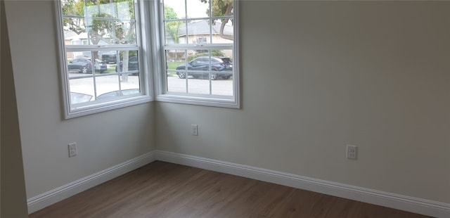 spare room with baseboards and wood finished floors