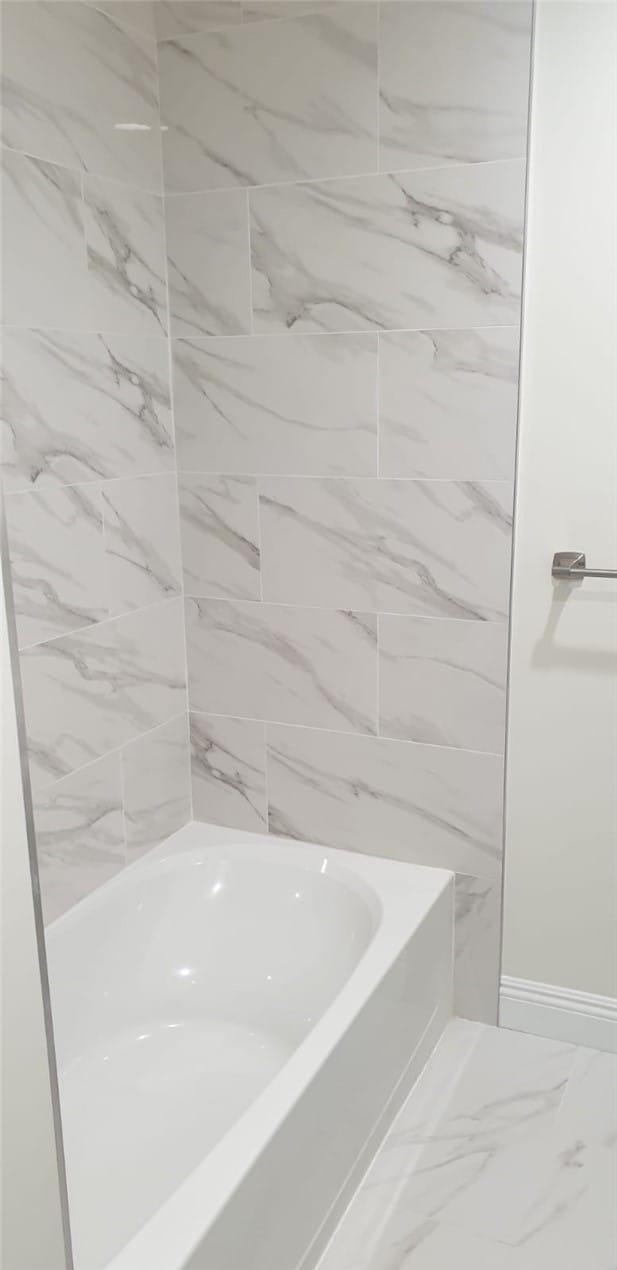 full bathroom featuring baseboards, a washtub, and marble finish floor