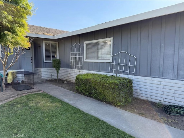 property entrance featuring board and batten siding and a yard