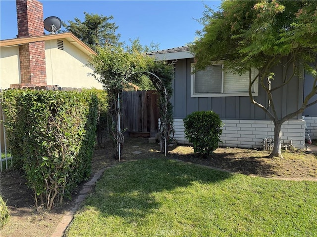view of side of home with a lawn, board and batten siding, a chimney, and stucco siding