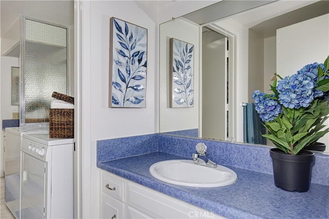 bathroom featuring washing machine and clothes dryer and vanity