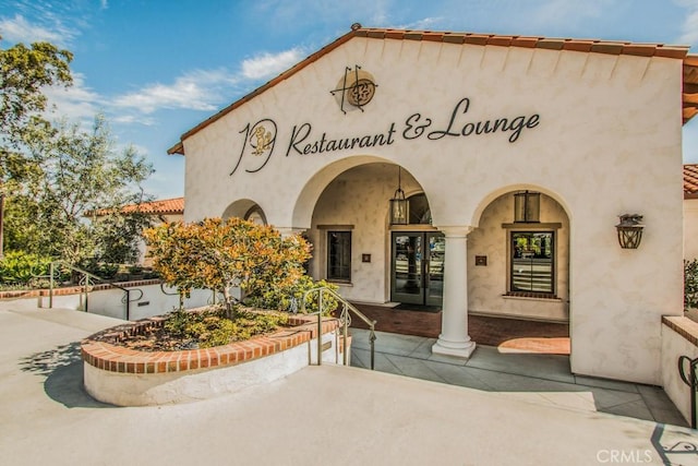 view of exterior entry featuring stucco siding and french doors