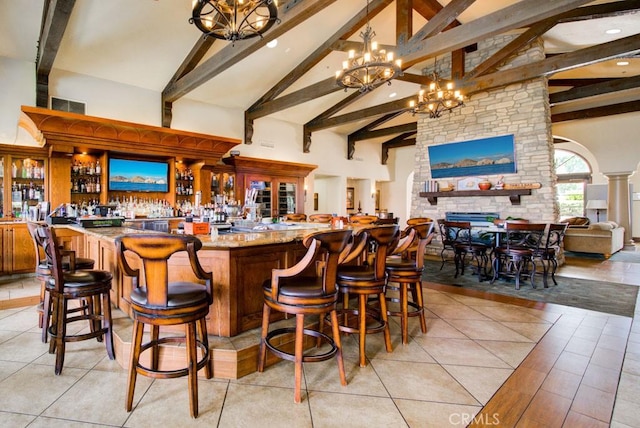 bar with high vaulted ceiling, indoor wet bar, visible vents, a notable chandelier, and beam ceiling