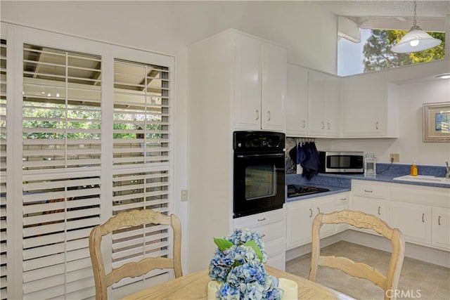kitchen featuring a sink, pendant lighting, black appliances, and white cabinetry