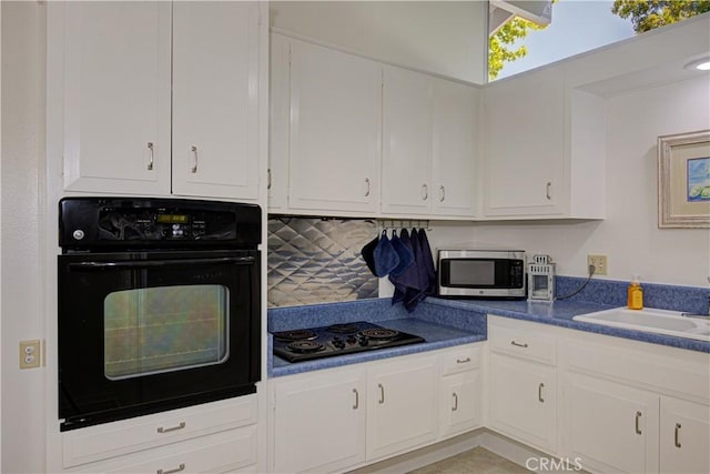 kitchen featuring a sink, dark countertops, black appliances, white cabinetry, and backsplash