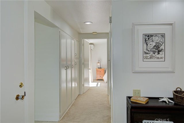 corridor featuring a textured ceiling and light colored carpet