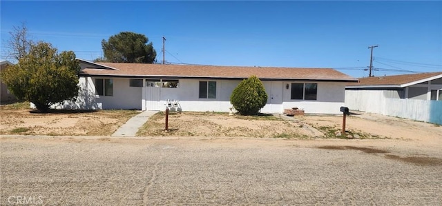 ranch-style house with stucco siding and fence