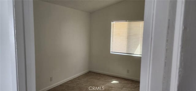 empty room with baseboards and lofted ceiling